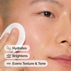 Close-up of a person applying 's Milky Toner with a cotton pad. Text overlays highlight the product's benefits: Hydrates, Brightens, and Evens Texture & Tone for healthier-looking skin.